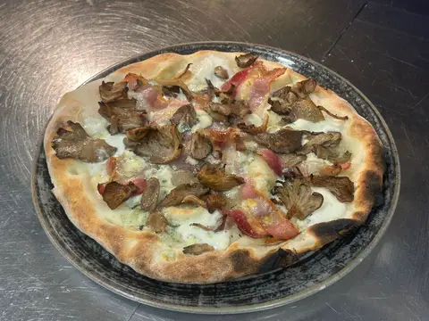 Pizza eTrigu servita su tavolo con condimenti ben visibili