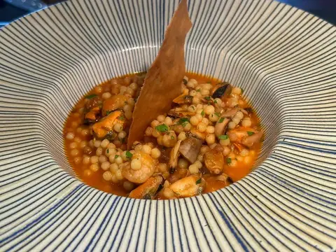 Fregola con frutti di mare servita in una ciotola rigata