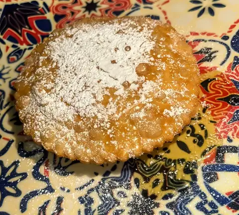 Dolce fritto con miele e zucchero a velo su piatto decorato